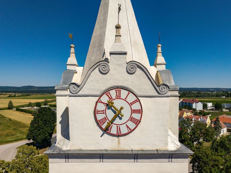 Kirchturm mit Turmuhr und verblechten Gesimsen