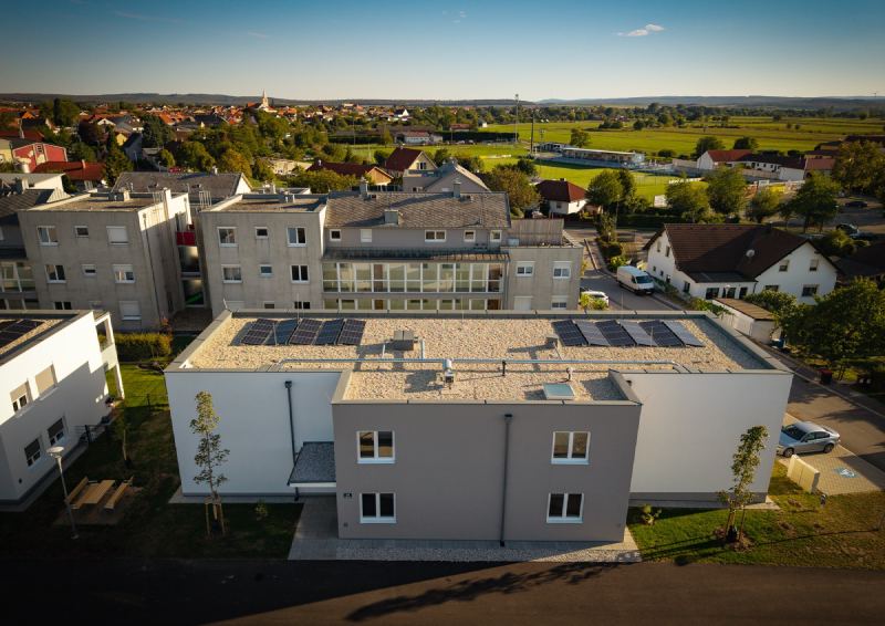 Wohnhaus mit Flachdach, dahinter St. Margarethen im Abendlicht